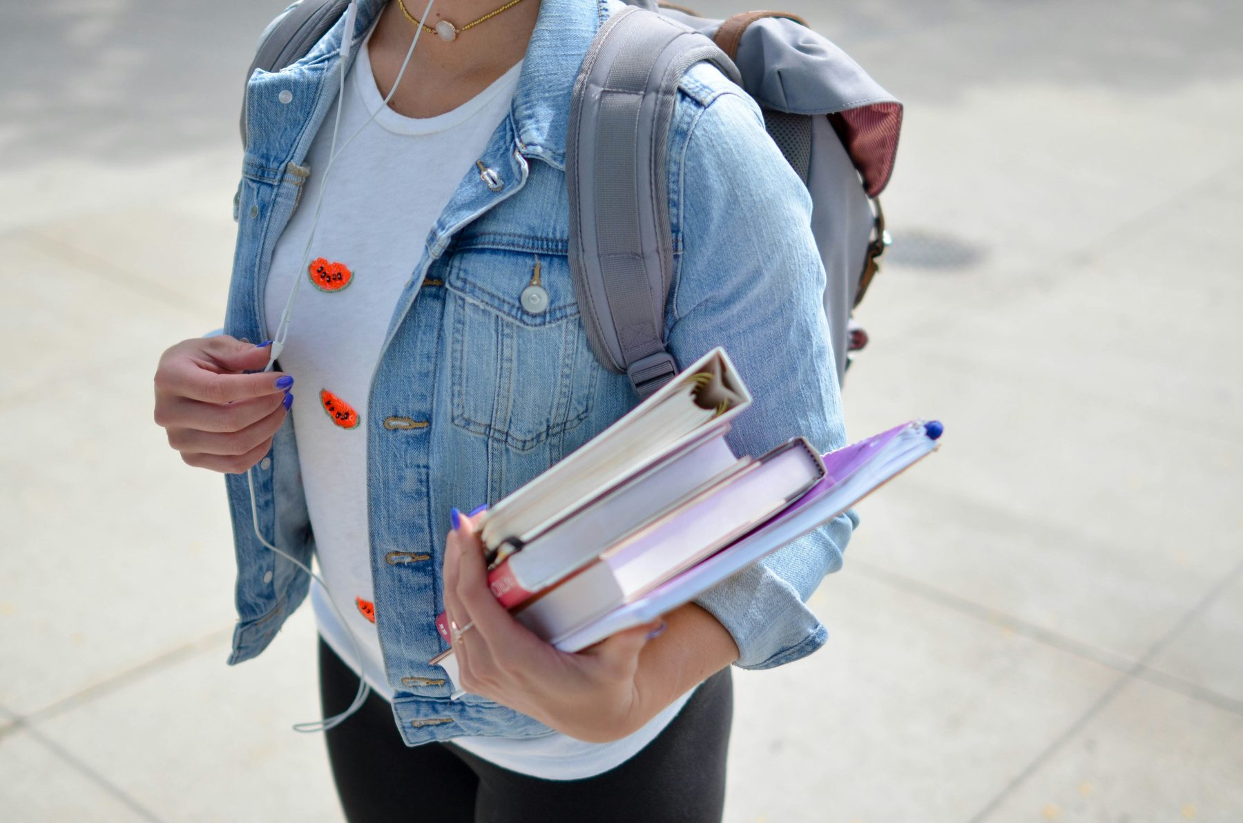 Student carrying books and a backpack on campus